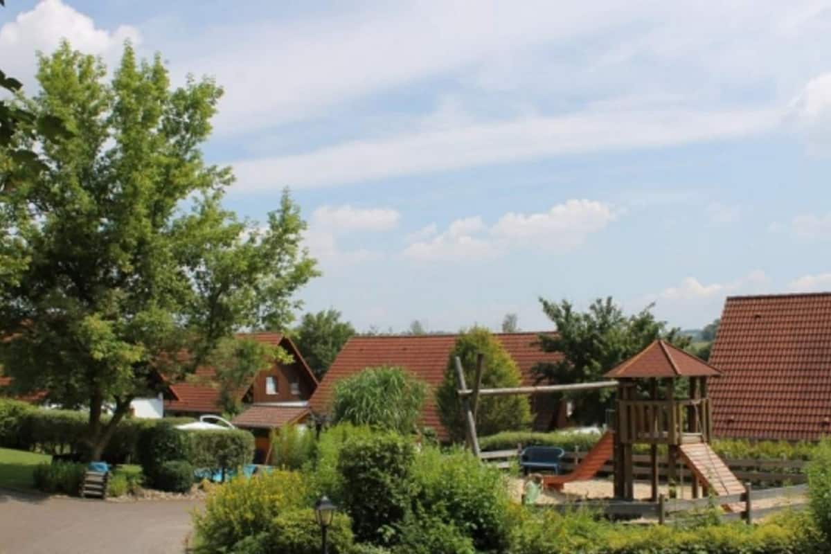 A residential area with multiple houses, a paved driveway, and a playground structure.