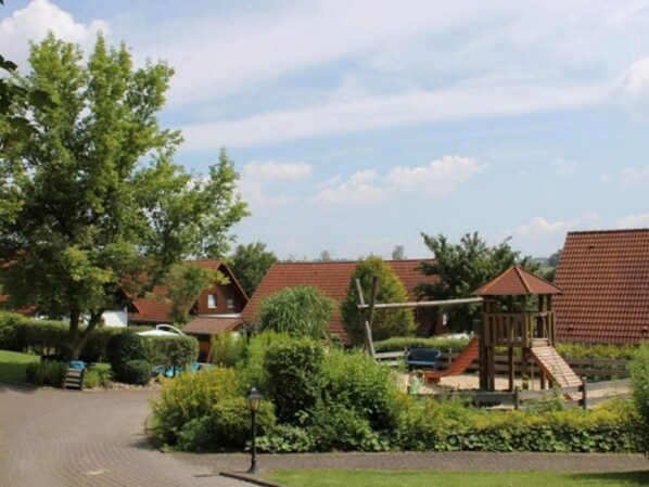 A residential area with multiple houses, a paved driveway, and a playground structure.
