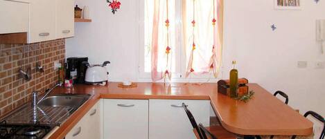 A compact kitchen with a gas stove, sink, and a small dining area with a table and chairs.