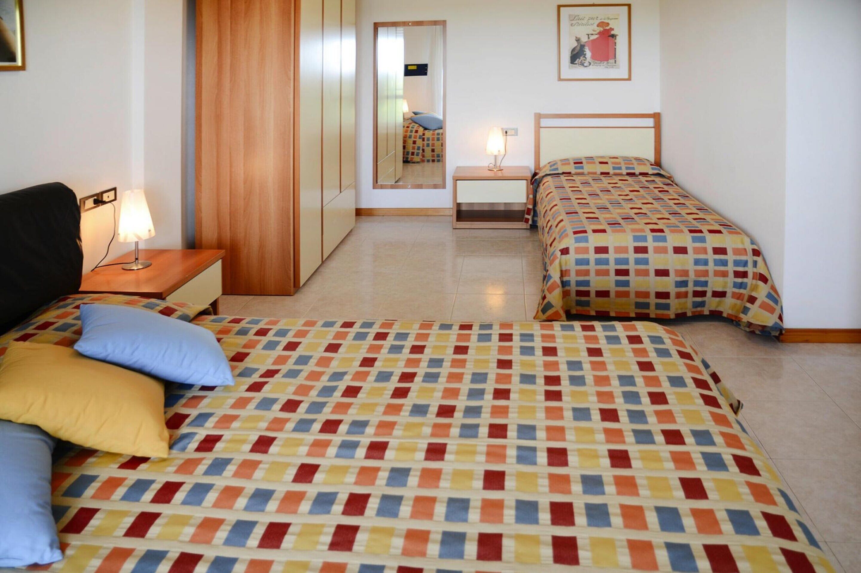 Ein Schlafzimmer mit zwei Betten, einem Nachttisch, einem Spiegel und einem Wandbild.