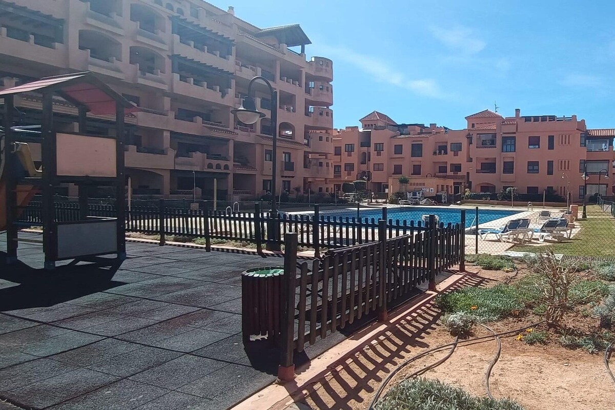 Un immeuble résidentiel doté de nombreux balcons, d’une piscine et d’un jardin clos.