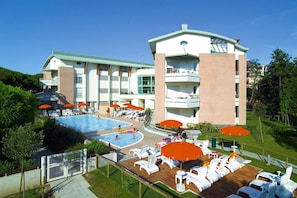 A hotel with a swimming pool, lounge chairs, and umbrellas. - Holiday Resort Parco e Acacie, Bibione Pineda (San Michele al Tagliamento)