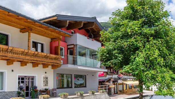 A modern building with a wooden balcony, a glass storefront, and a sign for 'IDEENKUCHEN'.