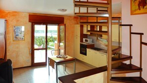 Cocina compacta con comedor, una escalera y vistas a través de un ventanal.