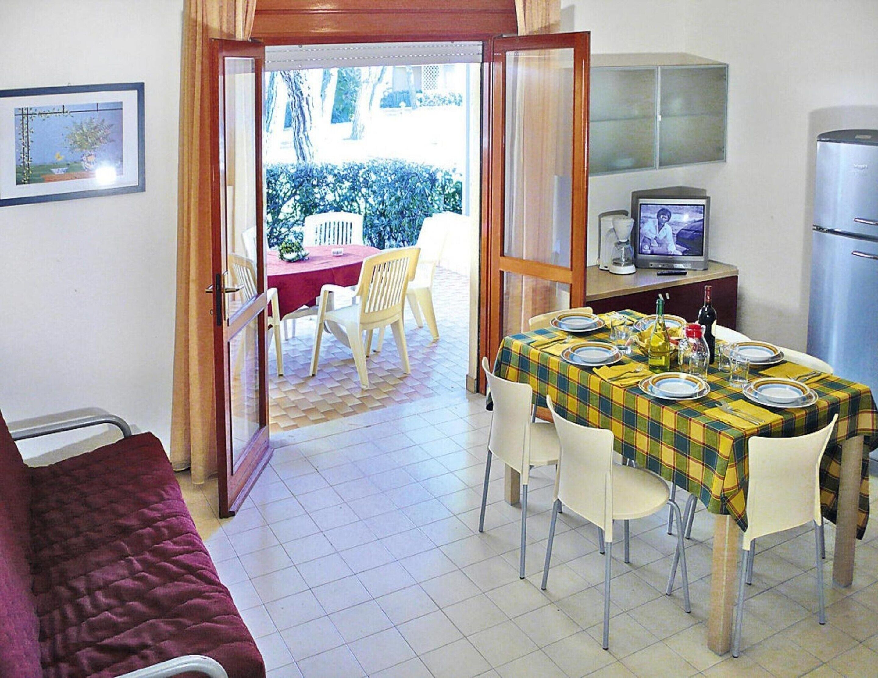 Un coin repas avec une table dressée pour quatre personnes, un téléviseur et un réfrigérateur.