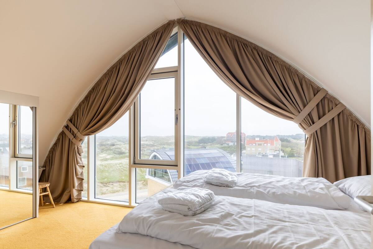 Un dormitorio con un ventanal grande, una cama y una silla.