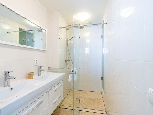 A modern bathroom with a glass-enclosed shower, a white sink, and a mirror above the vanity.