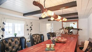 Een eetruimte met een houten tafel, lederen stoelen en hanglampen.