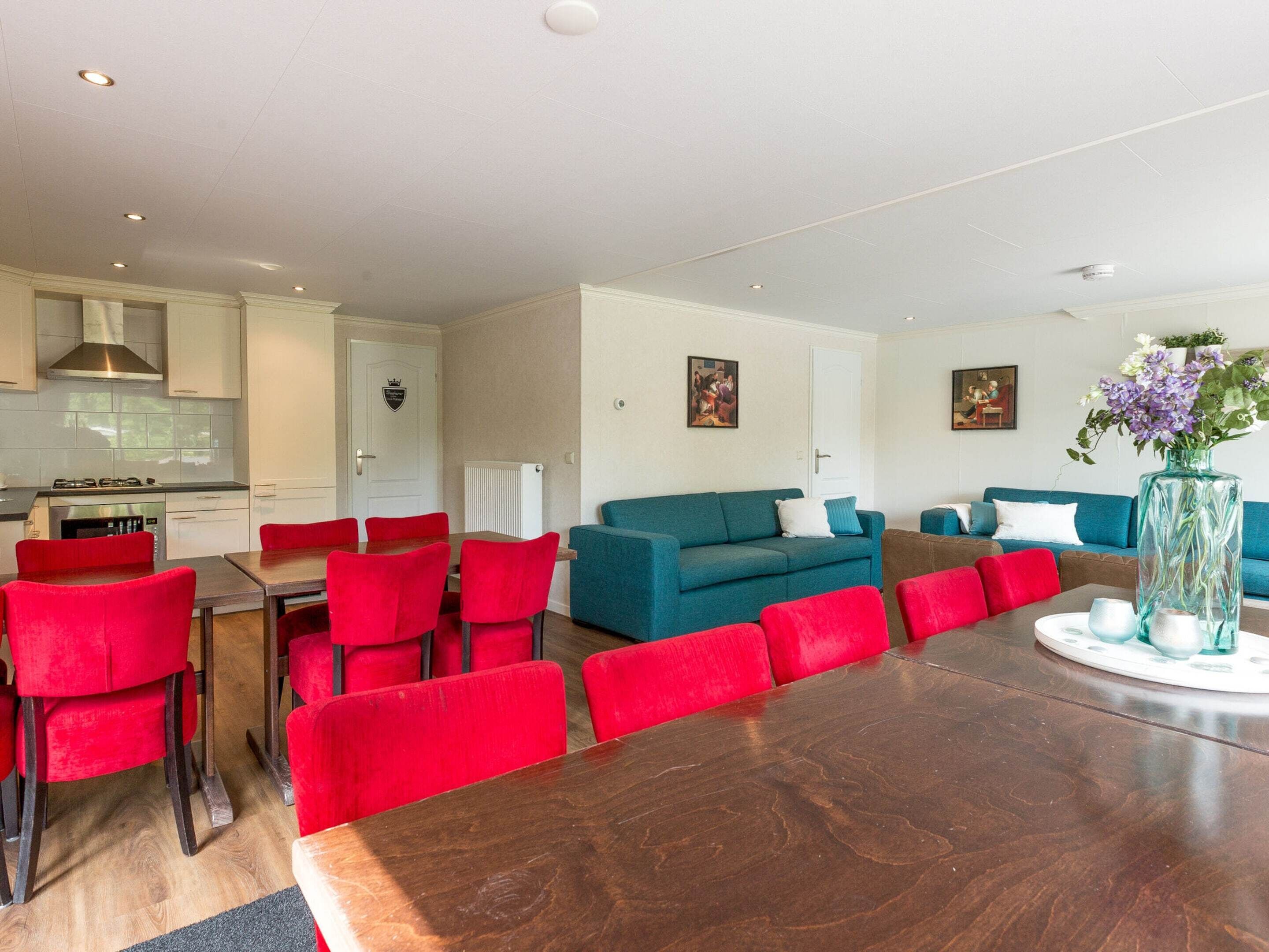 A modern living room with a dining area, a kitchen, and a blue sofa.