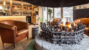 Zona de bar con sillones de cuero, chimenea y barra repleta de licores.