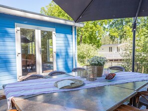 A covered patio with a table set for dining, featuring wicker baskets, candles, and a potted plant. - Beautiful House With Sandy Beach, Near Giethoorn (De Bult)