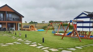 Propiedad residencial con una casa grande, una zona de juegos con tobogán y un cobertizo pequeño.