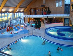An indoor swimming pool with multiple lanes, a children's play area, and a seating area with a view of the pool. - Holiday Home in Wernigerode With a Shared Pool (Wernigerode)