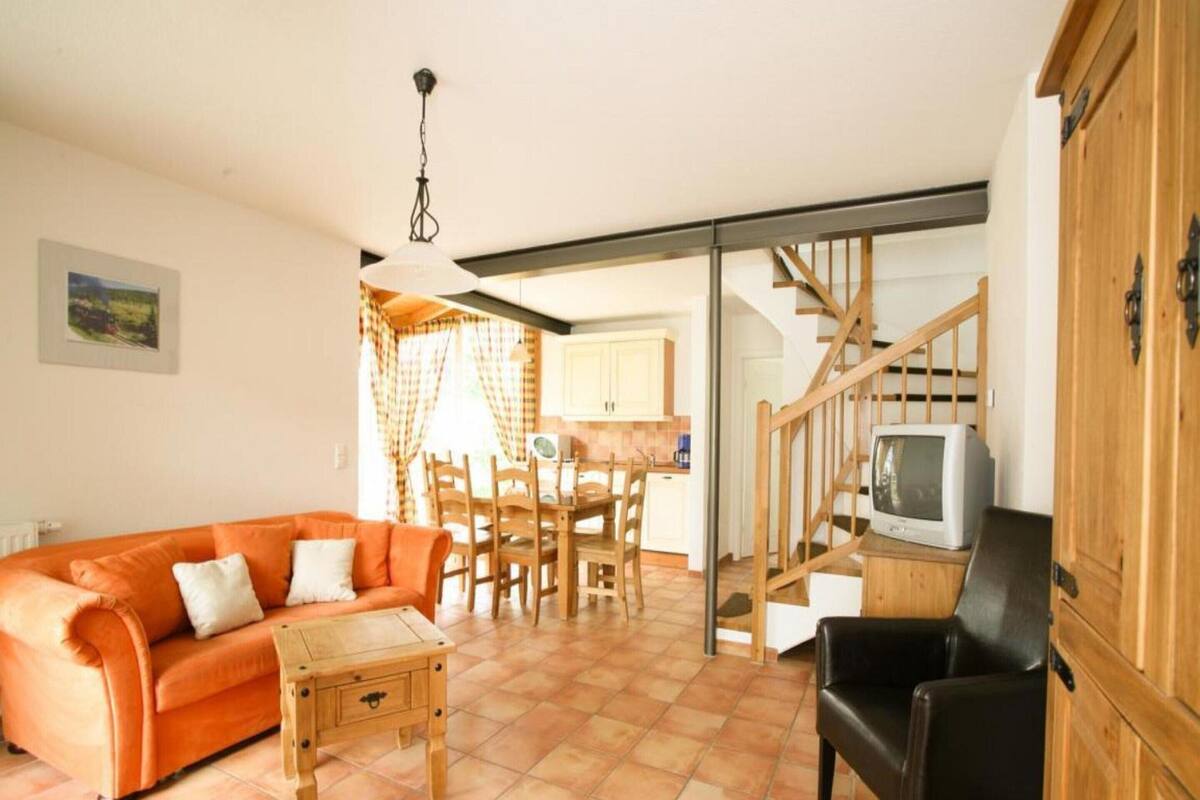 A living room with a sofa, a small table, a TV, and a staircase leading to another room.