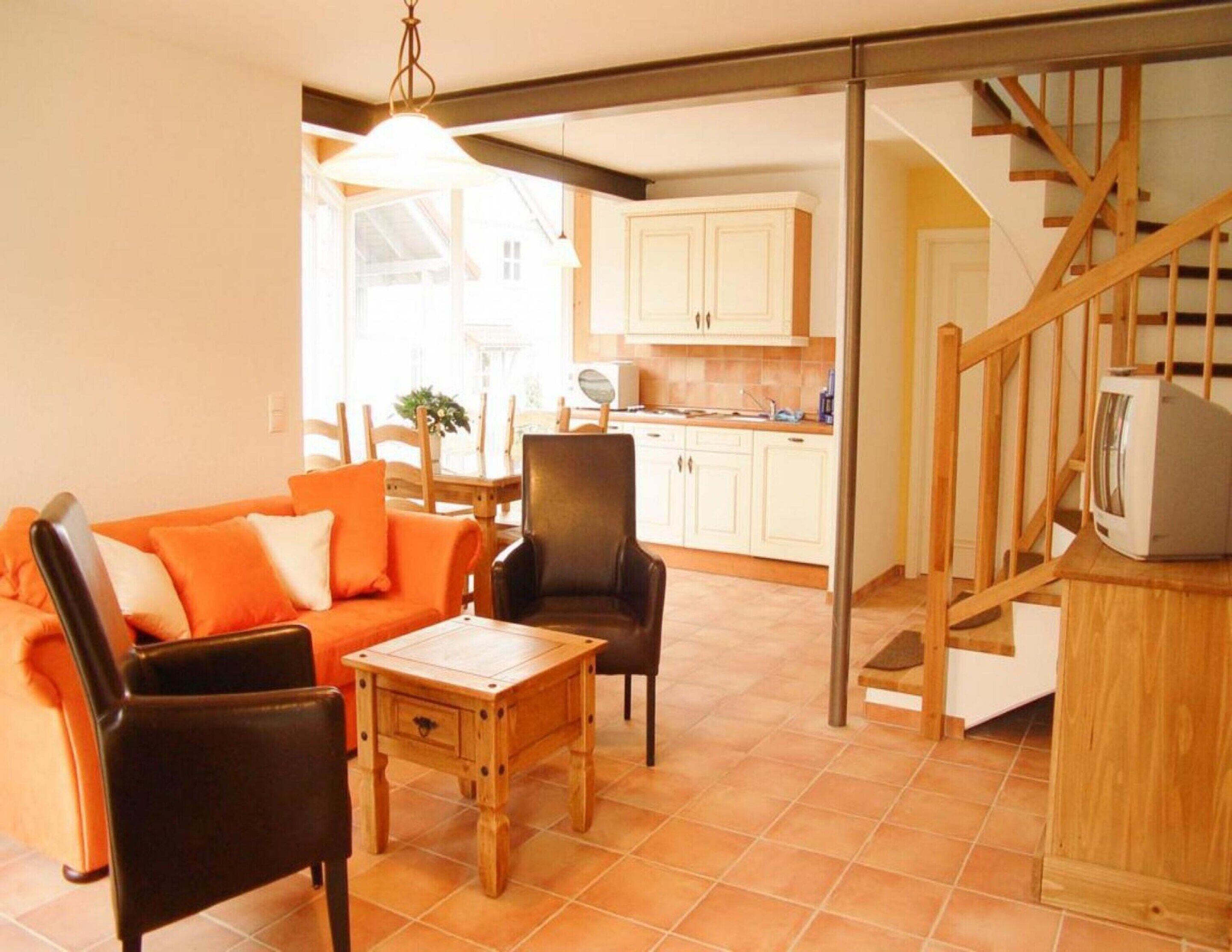 Un salon confortable avec un canapé, des fauteuils, une table basse et une cuisine en arrière-plan.