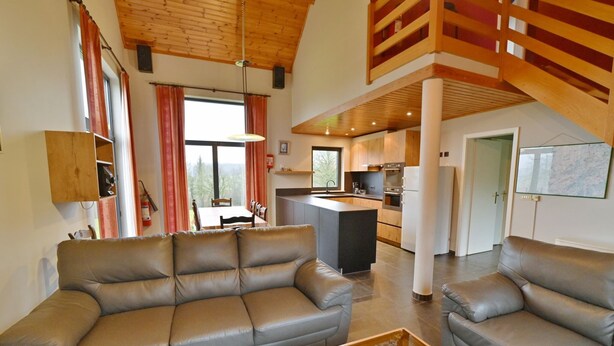 A spacious living area with a large leather sofa, a glass coffee table, and a view of the kitchen and dining area. - Modern Holiday Home in Somme-leuze With Garden (Somme-Leuze)