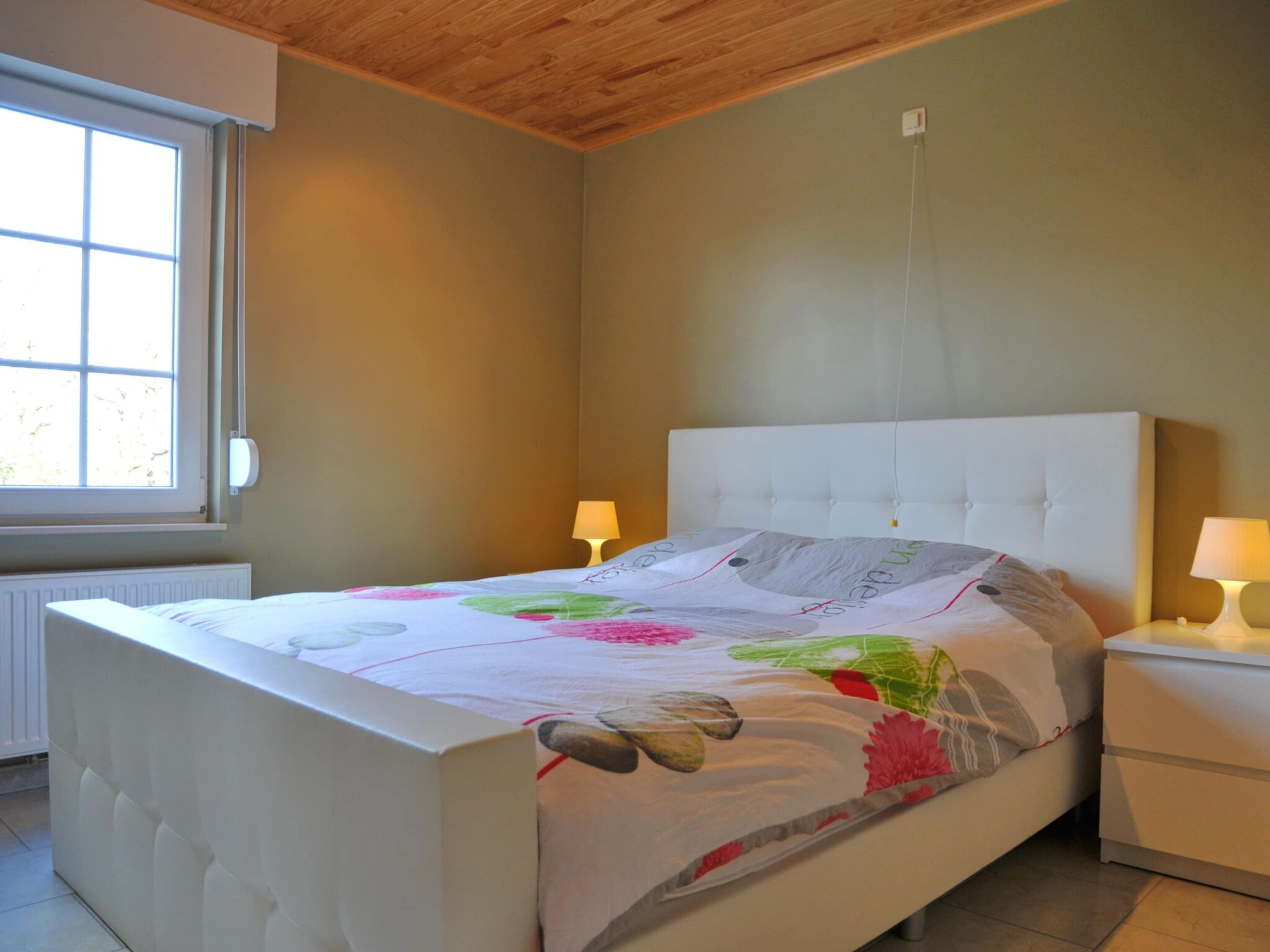Una camera da letto con un letto, due comodini, una finestra e un termosifone.