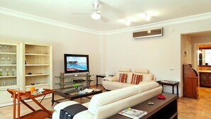 A living room with a sofa, coffee table, TV, and a wooden shelf unit.