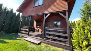 Een houten huis met twee verdiepingen, een overdekte veranda en een klein terras.