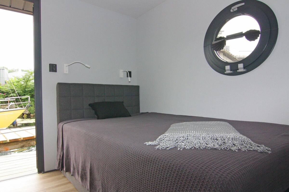 Une chambre à coucher avec un lit, un miroir rond et une fenêtre.