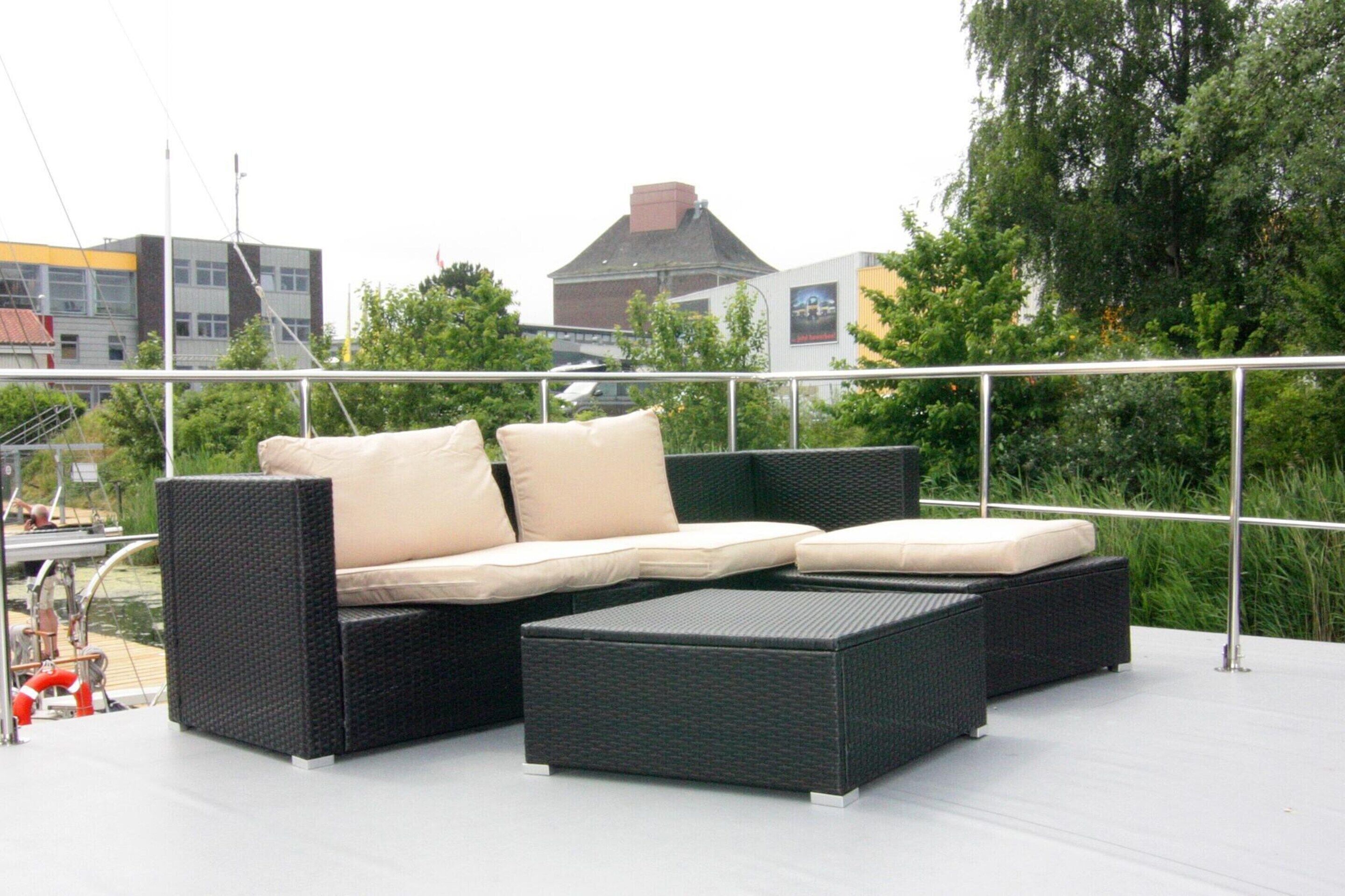 A black wicker sofa with beige cushions on an outdoor deck.