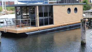 A wooden boat with a dining area and a small deck.
