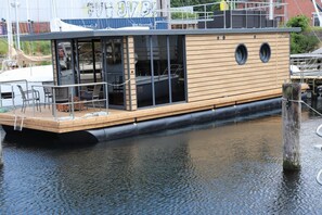 Een houten boot met een eethoek en een klein dek.