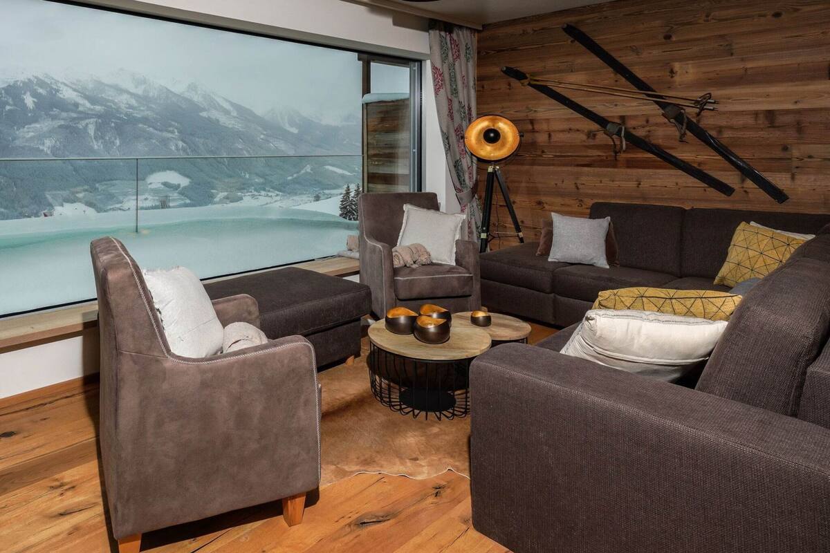A modern living room with a large window overlooking a snowy mountain landscape.