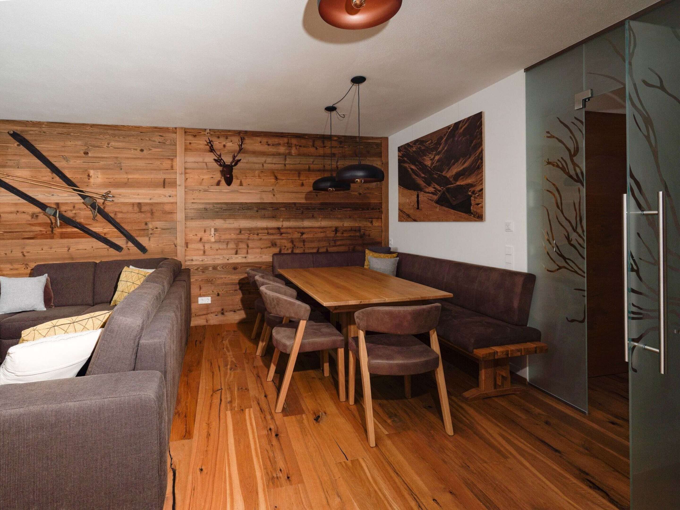 A cozy room with a wooden wall, a dining table, and a sofa.