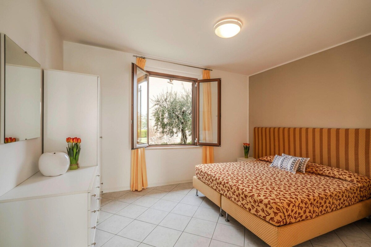 A bedroom with a bed, a dresser, a mirror, and a window with curtains.