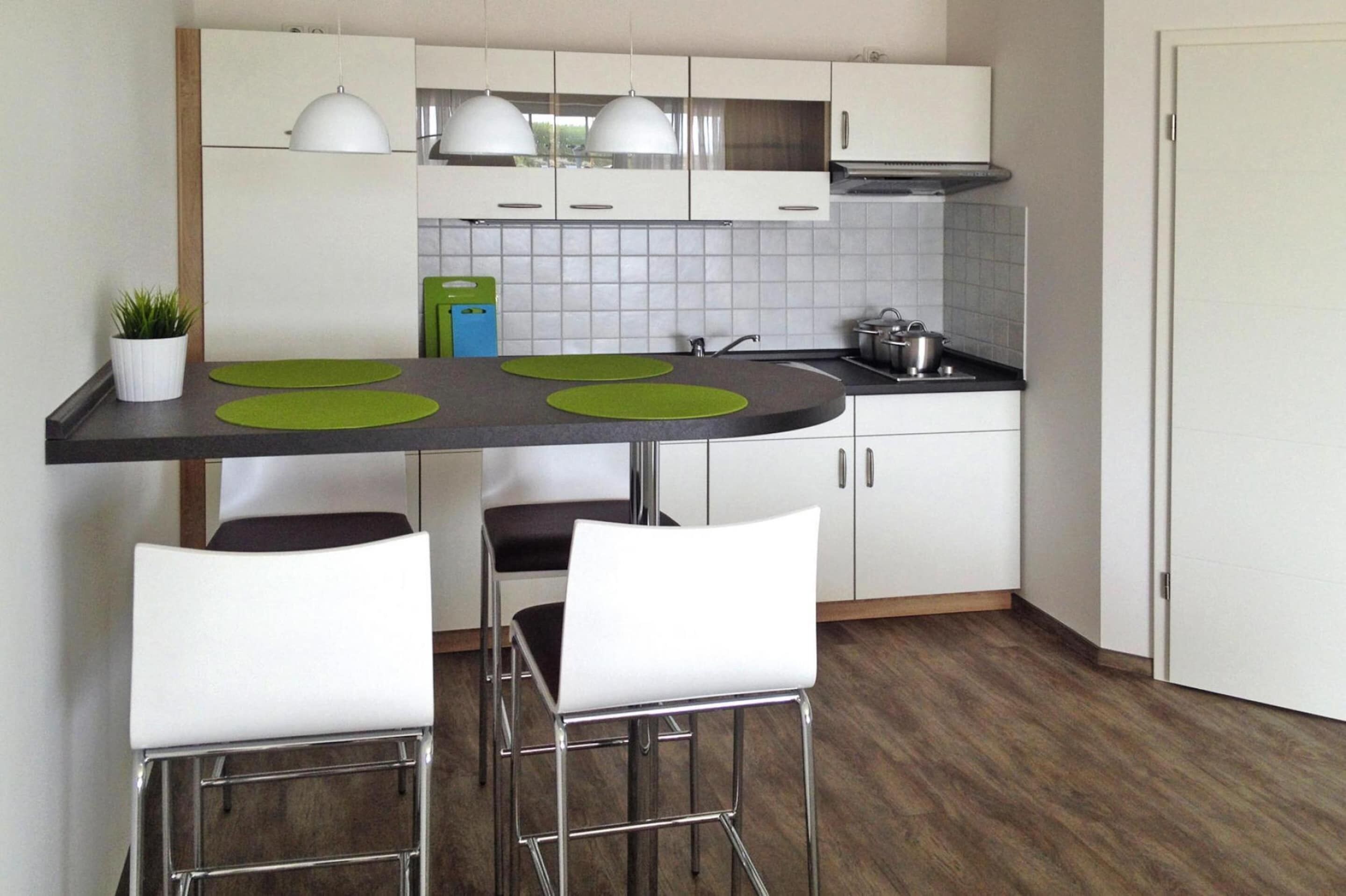 A modern kitchen with a central island, white cabinets, and a stainless steel range hood.