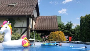 Ein Schwimmbecken mit Schwimmspielzeug, einer Steinmauer und einem Gebäude mit einem Ziegeldach.