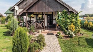 Ein Holzhaus mit Veranda, Satellitensch üssel und Garten mit verschiedenen Pflanzen.