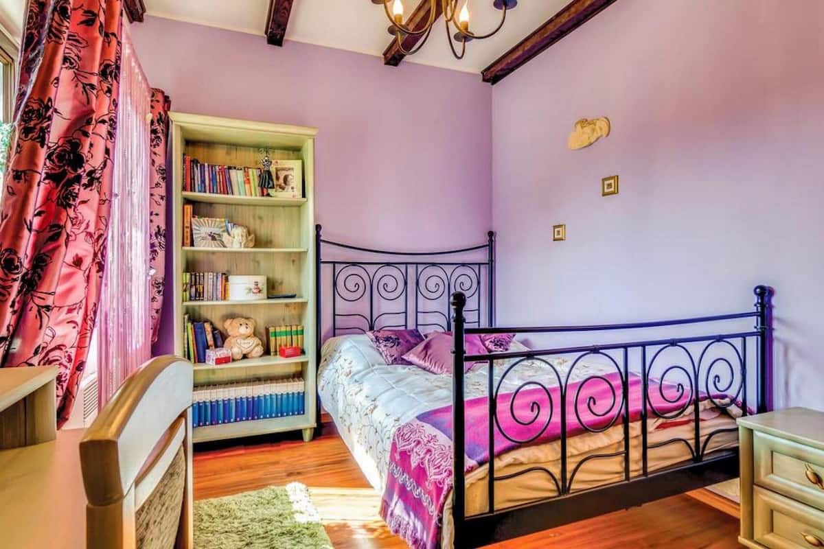 Un dormitorio con una cama, una estantería, una silla y un aparador.