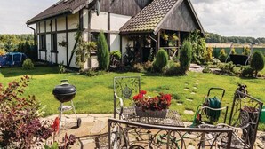Ein zweistöckiges Haus mit geneigtem Dach, umgeben von einem gepflegten Rasen und Garten.