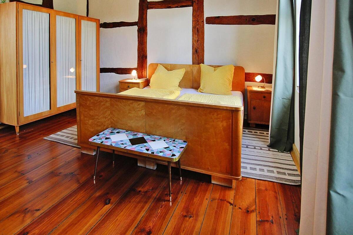 A bedroom with a wooden bed, a nightstand, a bedside table, and a wardrobe.