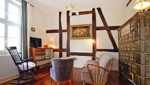 Una habitación acogedora con suelo de madera, una estantería, un televisor y dos mecedoras.