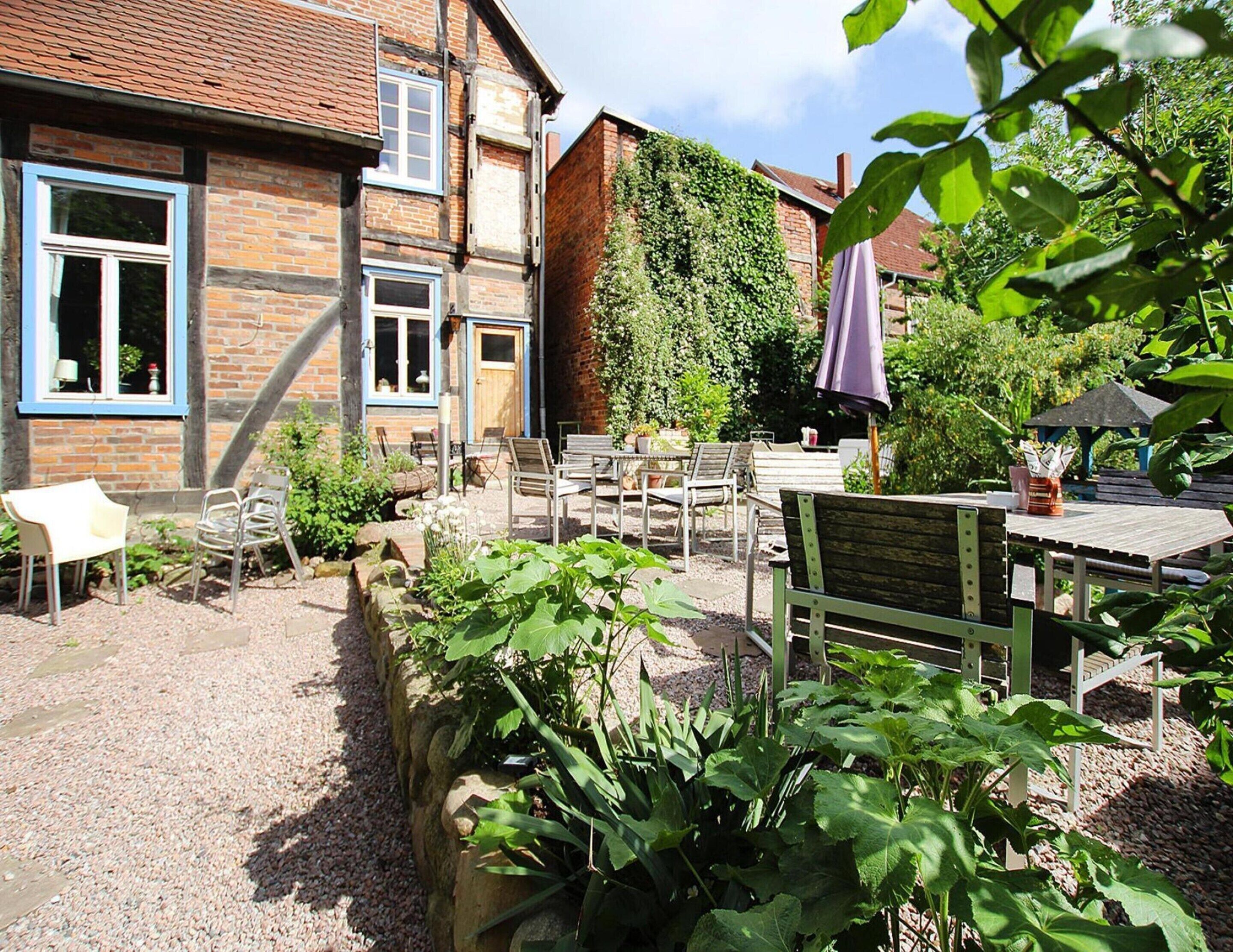 A courtyard with outdoor seating, a brick building, and a garden area.