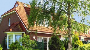 A two-story house with a red-tiled roof, large windows, and a well-maintained garden. - Reihenhaus, Dornumersiel (Dornum)