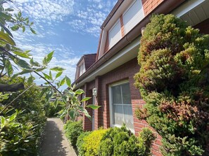A brick house with a window, a pathway, and various plants. - Reihenhaus, Dornumersiel (Dornum)