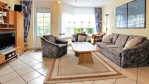 A living room with a TV, two armchairs, a sofa, and a coffee table. - Reihenhaus, Dornumersiel (Dornum)