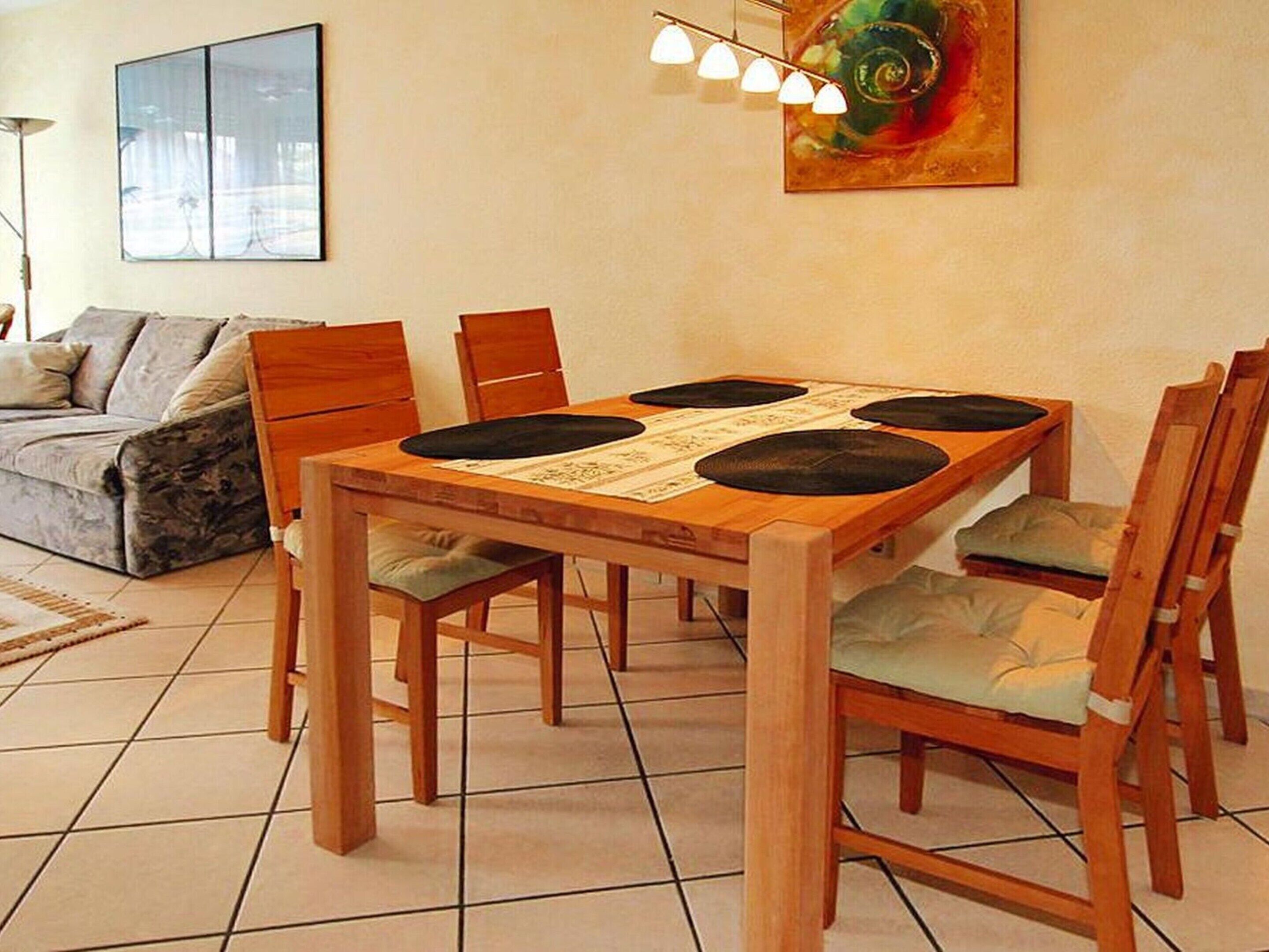A dining area with a wooden table, chairs, and a modern light fixture.