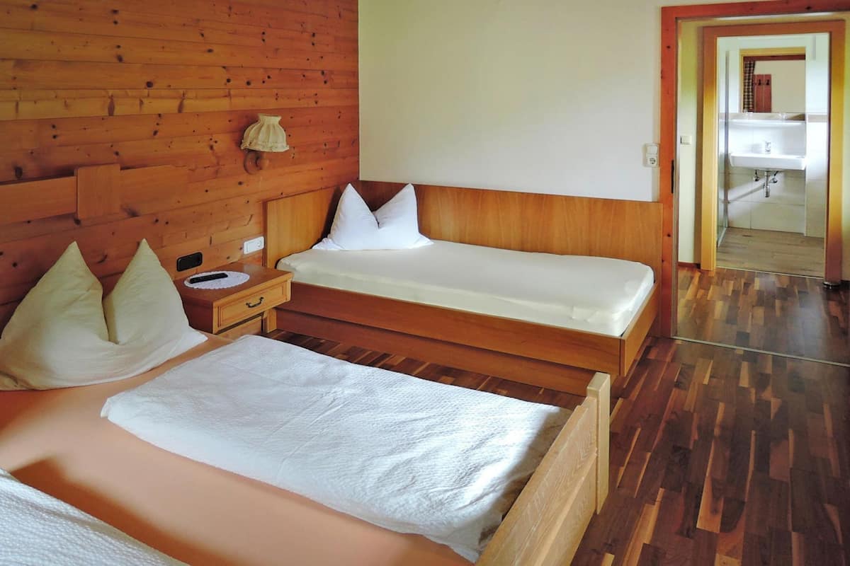 A wooden-paneled room with a bed, a nightstand, and a bathroom visible through an open door.