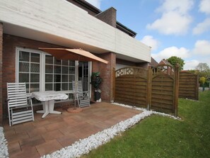 A patio with a table and chairs, a wooden gate, and a brick wall. - Apartment in a Quiet Location in Dornumersiel (Dornum)