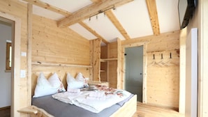 A wooden room with a bed, a wardrobe, and a door.