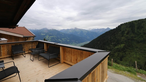 A wooden deck with outdoor seating and a view of mountains.