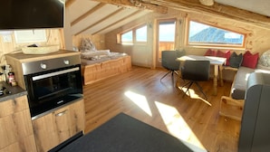 A cozy attic bedroom with a wooden ceiling, a bed, a small table, and a sofa.