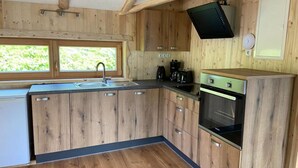 A compact kitchen with wooden cabinets, a built-in oven, a sink, and a window providing natural light.