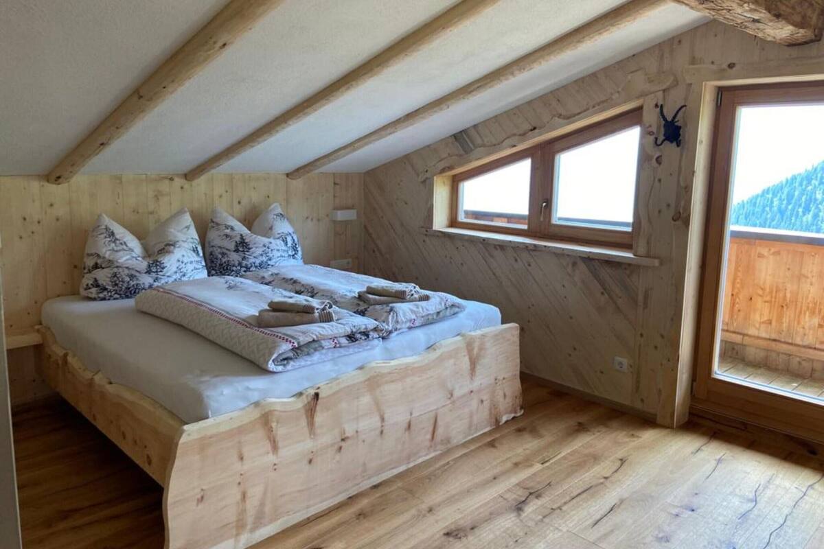 A wooden bedroom with a bed, pillows, and a window.