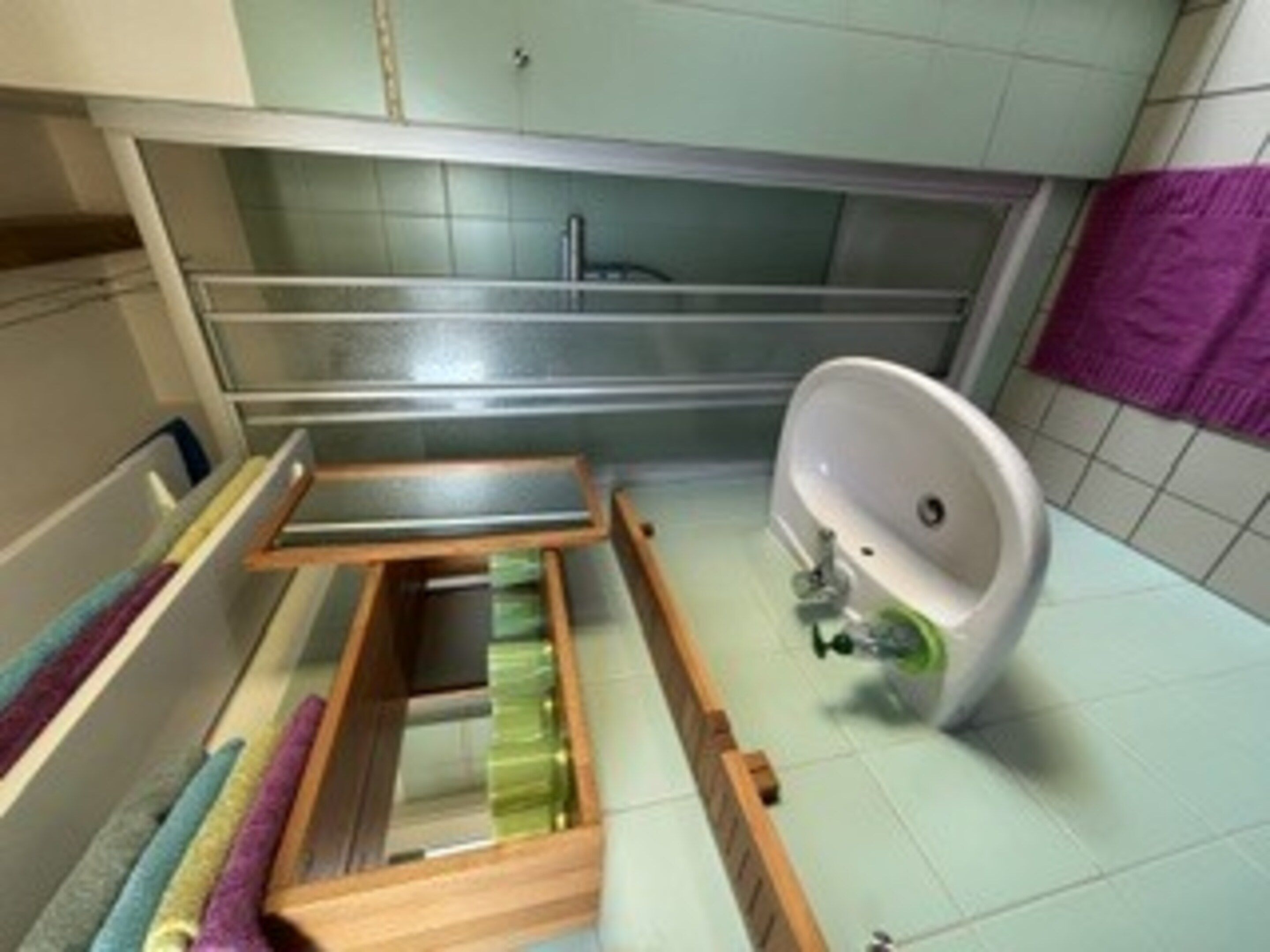 A bathroom with a built-in wooden shelf, a white sink, and a purple towel.